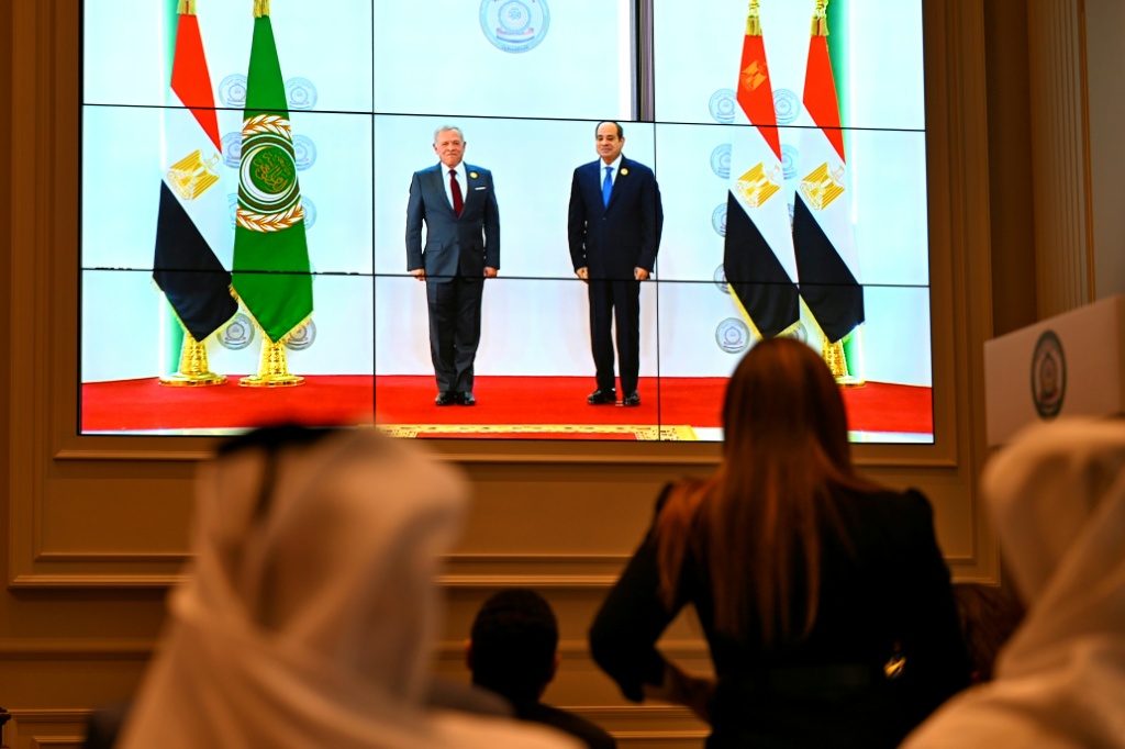 أشخاص يتابعون على شاشة كبيرة الرئيس المصري عبد الفتاح السيسي خلال استقباله ملك الأردن عبد الله الثاني قبل القمة العربية حول غزة في القاهرة، في الرابع من آذار/مارس 2025 (أ ف ب)   