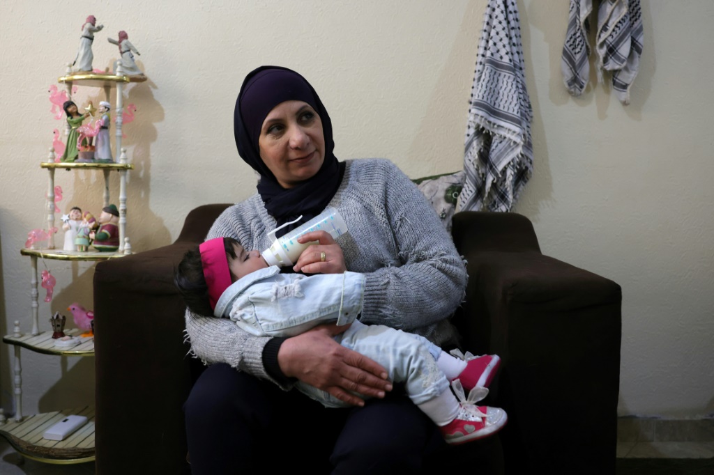 إيمان فرحات مع طفلتها بالتبني جنة في مدينة غزة (أ ف ب)   