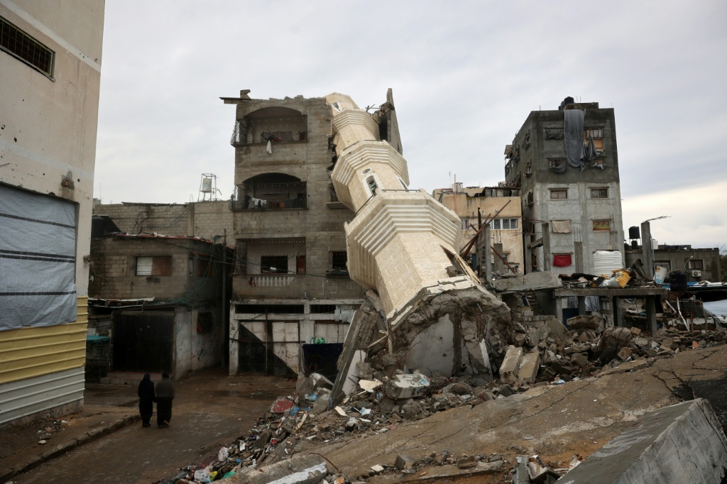 نساء فلسطينيات يسرن بالقرب من مئذنة مسجد مدمر خلال شهر رمضان في مخيم النصيرات للاجئين في وسط قطاع غزة في 7 آذار/مارس 2025 (أ ف ب)   