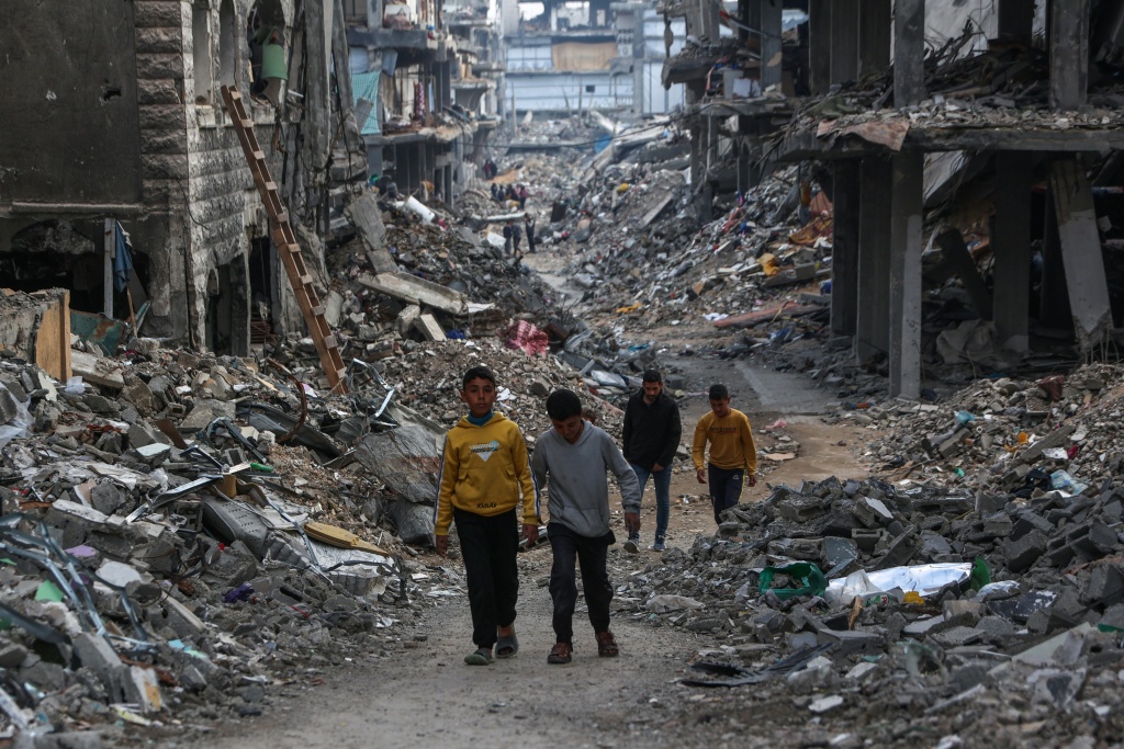 فلسطينيون بين أنقاض حي مدمّر في بيت لاهيا بشمال قطاع غزة في التاسع من آذار/مارس 2025 0أ ف ب)   