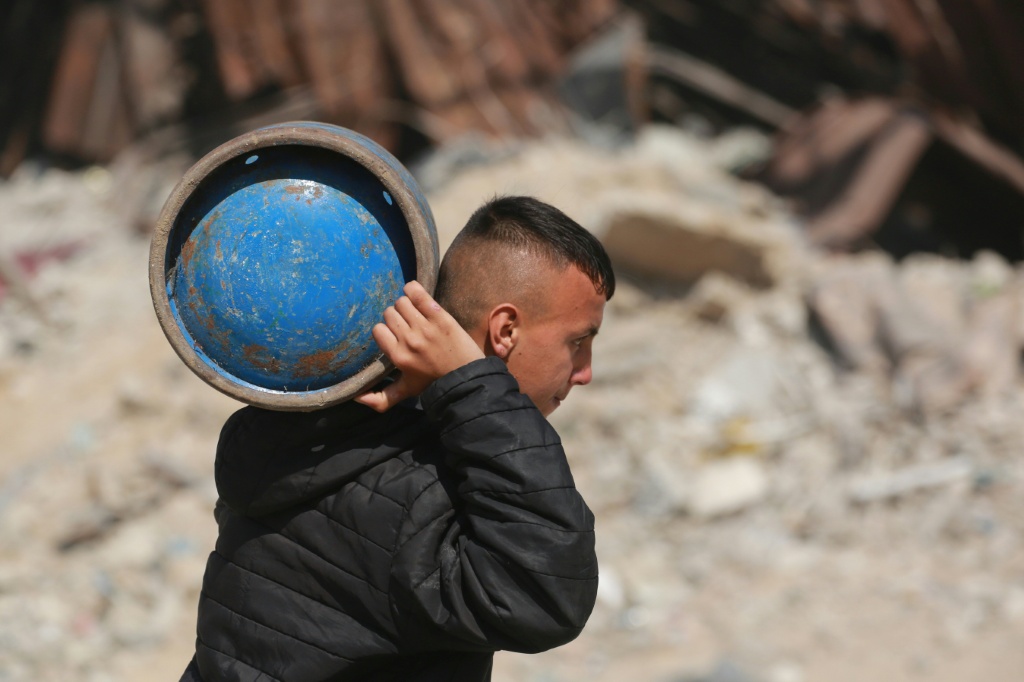 فلسطيني يحمل قارورة غاز على كتفه في مخيم للنازحين غرب مدينة جباليا في شمال قطاع غزة في 11 اذار/مارس 2025 (أ ف ب)   