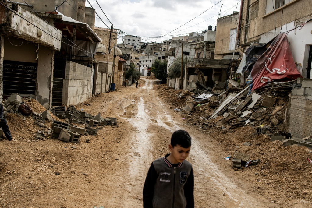 طفل فلسطيني يعبر حيا دمّرته القوات الإسرائيلية في شرق جنين في 13 شباط/فبراير 2025 (أ ف ب)   