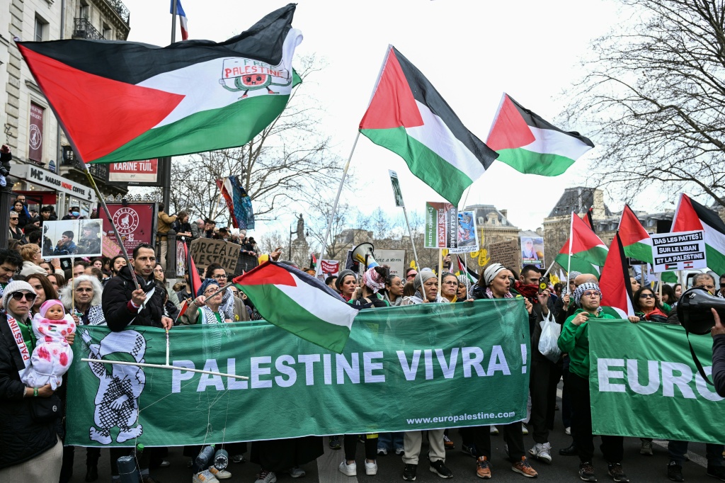 متظاهرون يلوحون بالأعلام الفلسطينية ويحملون لافتة كُتب عليها "فلسطين ستعيش" خلال تظاهرة في ساحة الجمهورية في باريس في 22 آذار/مارس 2025 ضمن اليوم الدولي ضد العنصرية والفاشية (أ ف ب)   