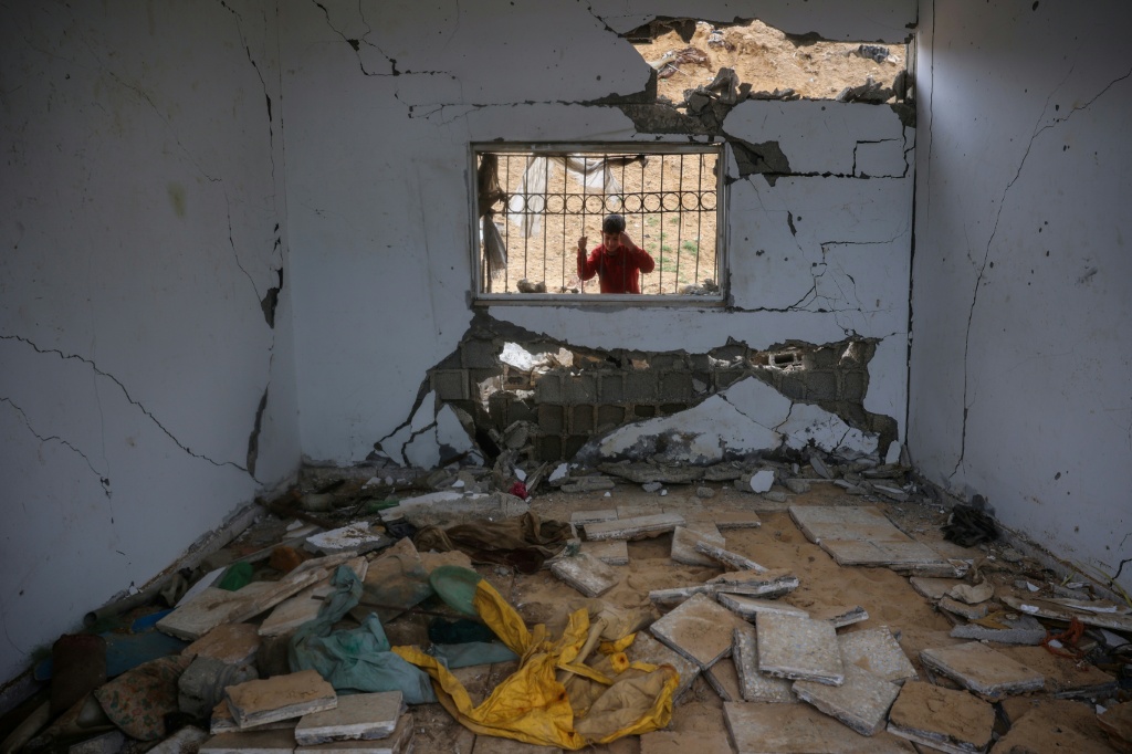 طفل فلسطيني ينظر إلى مبنى تضرر في غارة إسرائيلية سابقة في دير البلح في وسط قطاع غزة في 22 آذار/مارس 2025 (ا ف ب)   