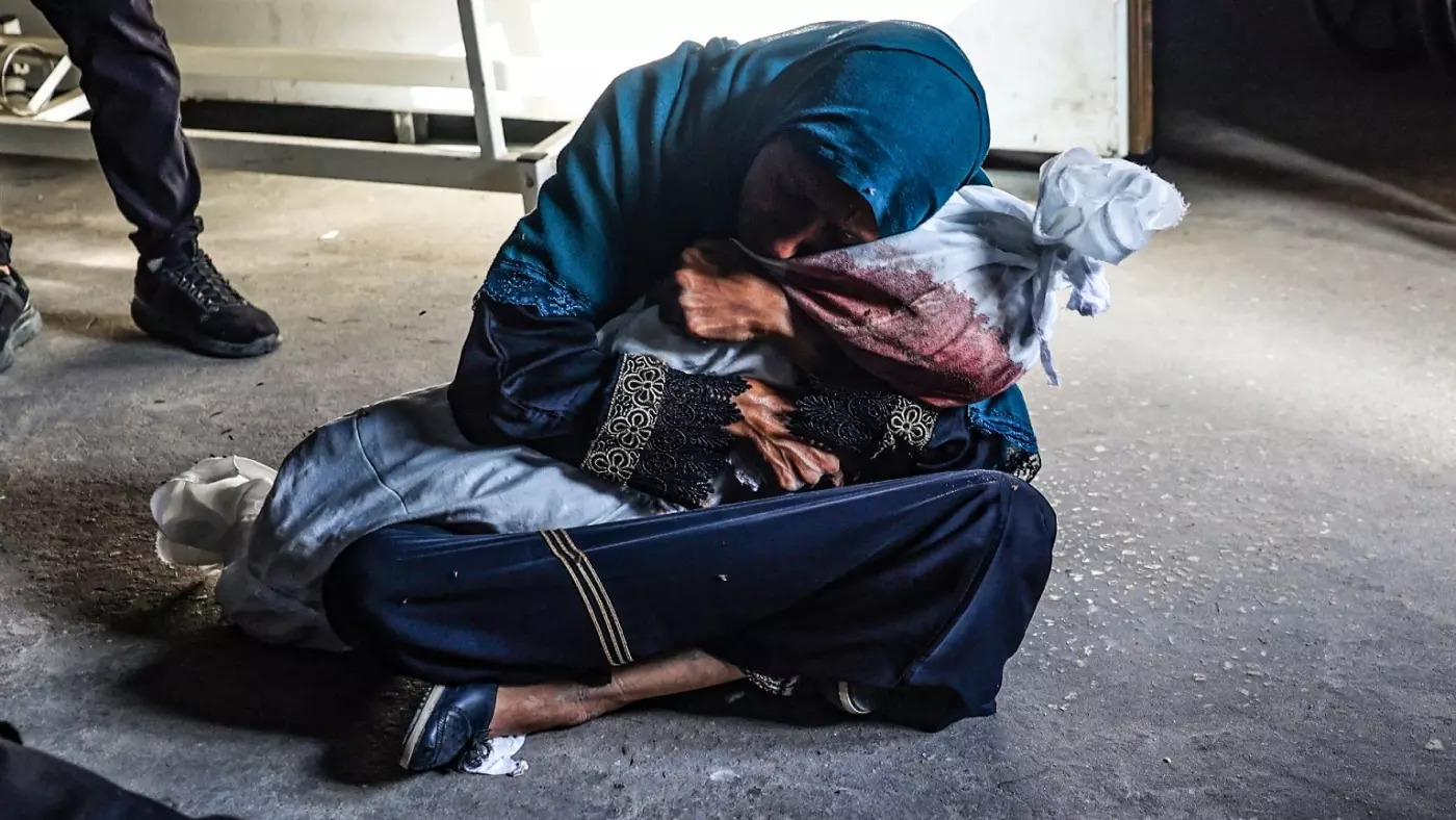 أم فلسطينية تحتضن طفلها الشهيد في غزة (أ ف ب)