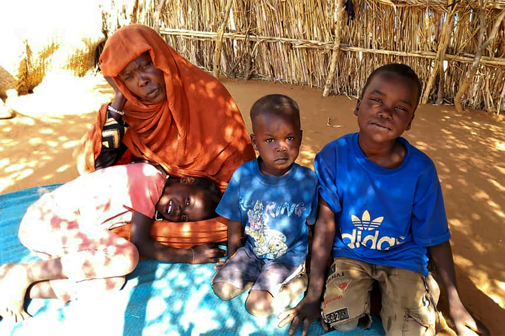 السودانية النازحة منى إبراهيم وأطفالها يجلسون على الأرض في مخيم زمزم للنازحين الذي أعلنت فيه المجاعة في شمال دارفور في 21 كانون الثاني/يناير 2025 (ا ف ب)   