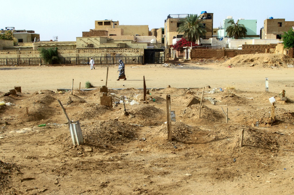امرأة تمر بقبور أشخاص قتلوا في الحرب في السودان بين الجيش وقوات الدعم السريع على امتداد شارع في أم درمان في ضاحية الخرطوم في 20 آذار/مارس 2025 (أ ف ب)   