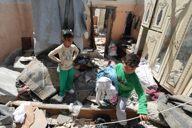 طفلان فلسطينيان يجمعان بعض الأمتعة من بين أنقاض منزل دمرته غارة إسرائيلية في خان يونس جنوب في قطاع غزة في 31 آذار/مارس 2025 (أ ف ب)