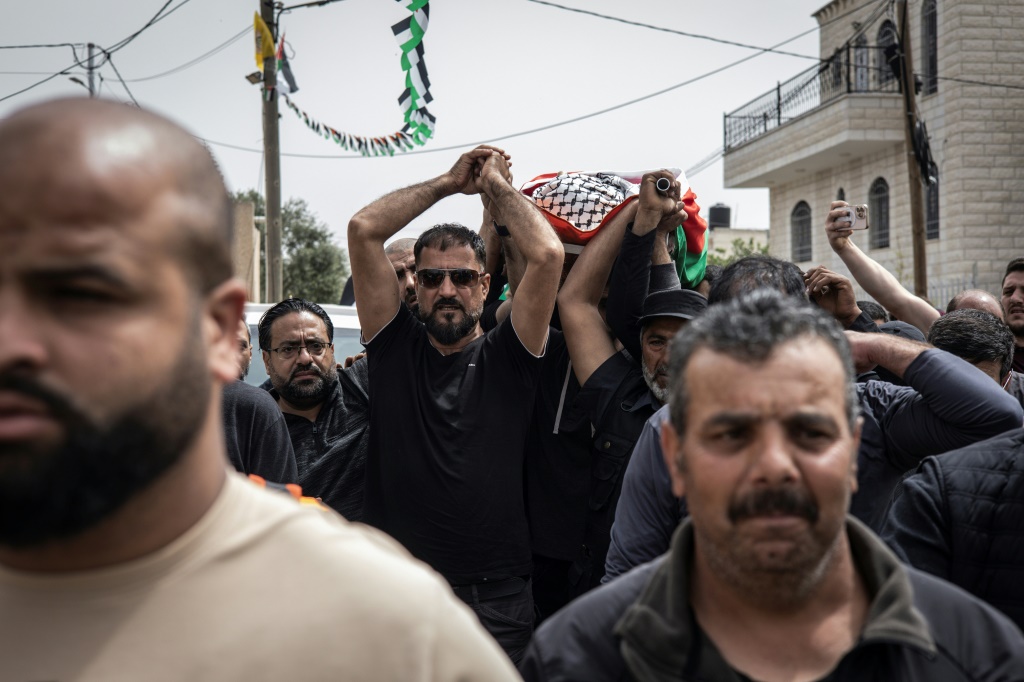 جثمان أمير ربيع (14 عاما) محمولا خلال جنازته في ترمسعيا في 7 نيسان/أبريل 2025 ويبدو والده (وسط) محمد ربيع وهو يشارك في حمل النعش (ا ف ب)   