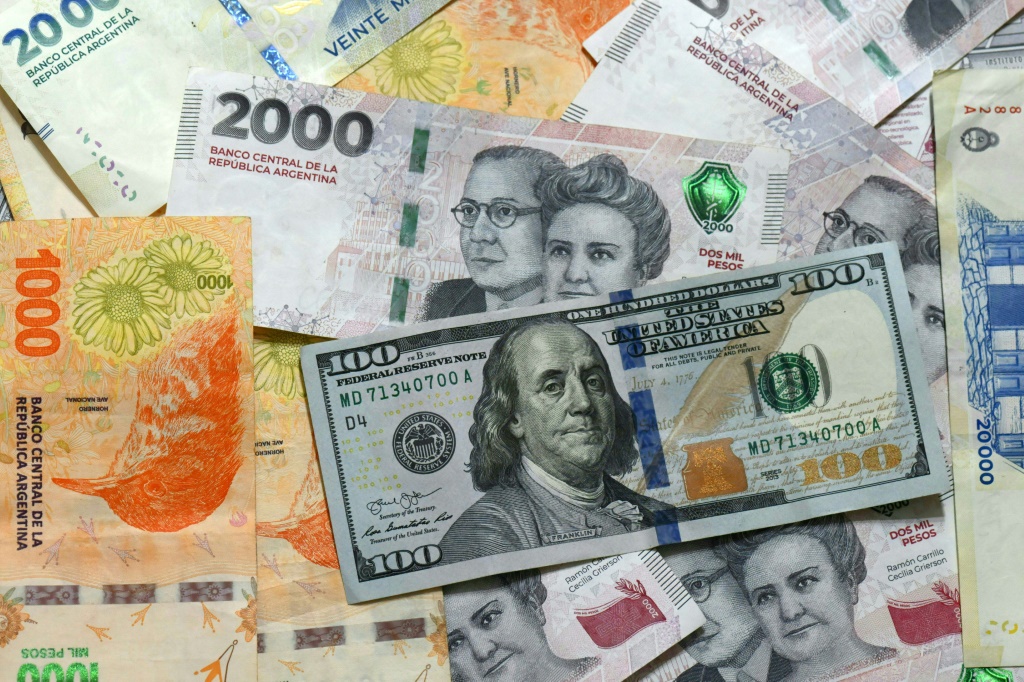    أوراق البيزو الأرجنتيني وورقة من فئة 100 دولار أميركيّ في 11 نيسان/أبريل 2025 في بوينس آيرس (ا ف ب)   