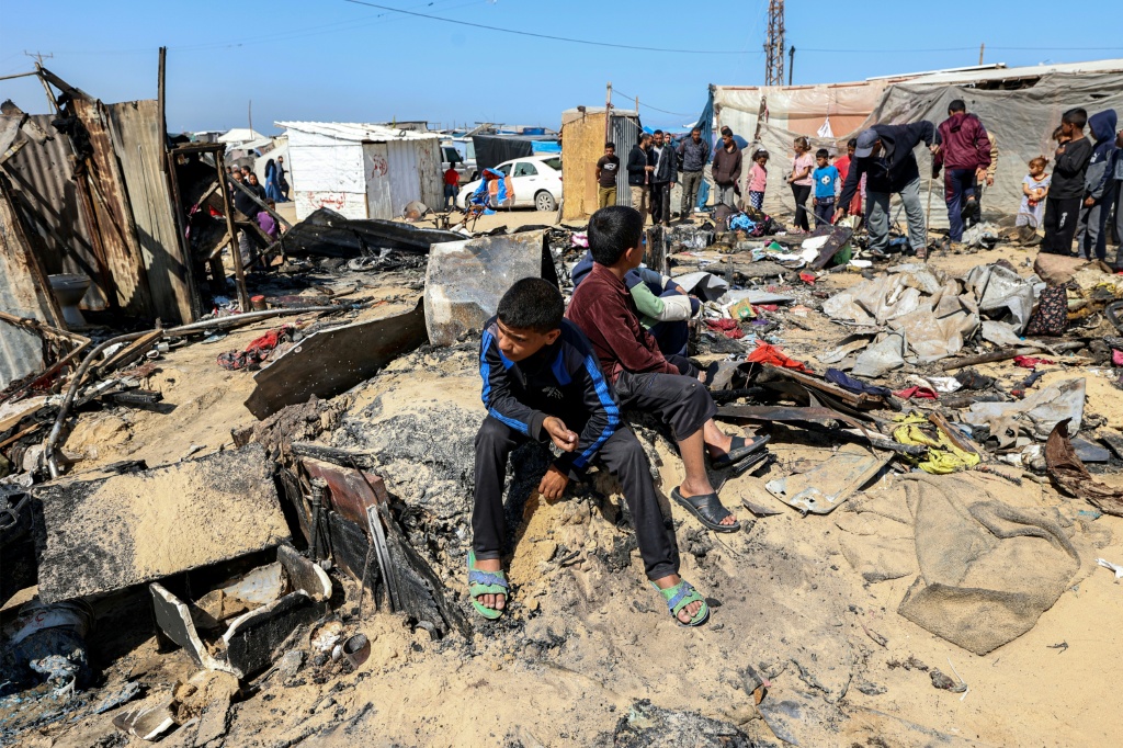  أطفال جالسون بين أنقاض خيم للنازحين استهدفت بضربات إسرائيلية في خان يونس بجنوب قطاع غزة في 17 نيسان/ابريل 2025 (أ ف ب)   