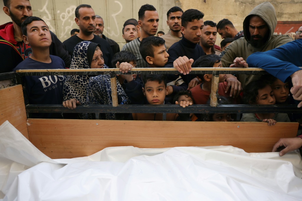 فلسطينيون يتجمعون حول جثث مغطاة قبل نقلها للدفن بعد الغارات الإسرائيلية الليلية على منطقة نزلة جنوب غرب جباليا والتي أسفرت عن مقتل وإصابة عدد من الأشخاص من نفس العائلة، في شمال قطاع غزة في 16 نيسان/أبريل 2025 (أ ف ب)   