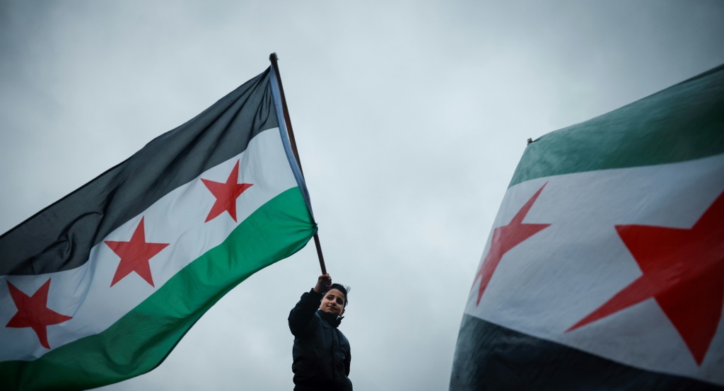    متظاهر يرفع العلم السوري الجديد احتفالا بسقوط نظام الأسد وسط لندن بتاريخ 8 كانون الأول/ديسمبر 2024 (أ ف ب)   