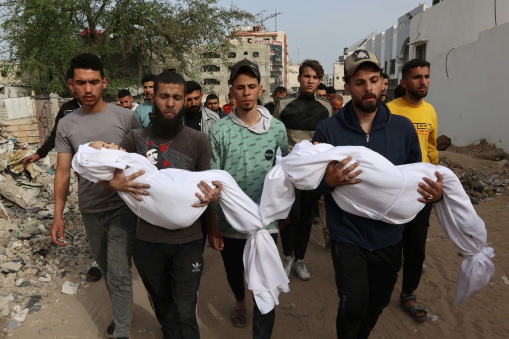 فلسطينيون يحملون جثامين أقارب لهم قتلوا في غارة إسرائيلية على مدرسة استحالت ملجأ خلال تشييعهم قرب مستشفى الشفاء في مدينة غزة في 23 نيسان/أبريل 2025 (أ ف ب)   