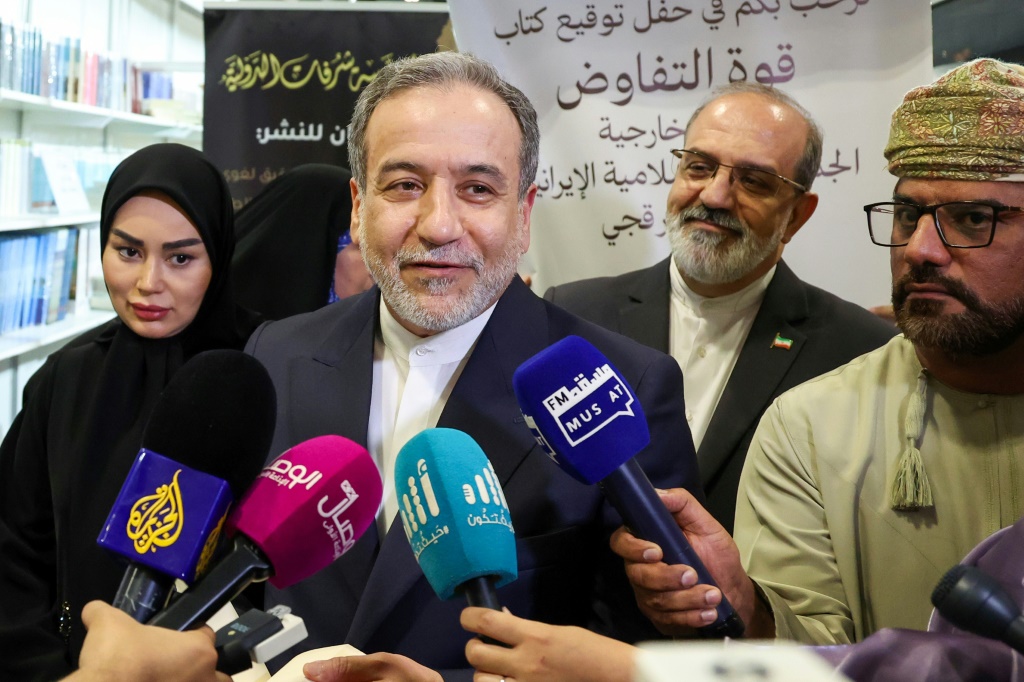وزير الخارجية الإيراني عباس عراقجي (وسط) يتحدث إلى الإعلام أثناء حقل توقيع كتابه "قوة التفاوض" في معرض مسقط للكتاب في 25 نيسان/ابريل 2025 (أ ف ب)   
