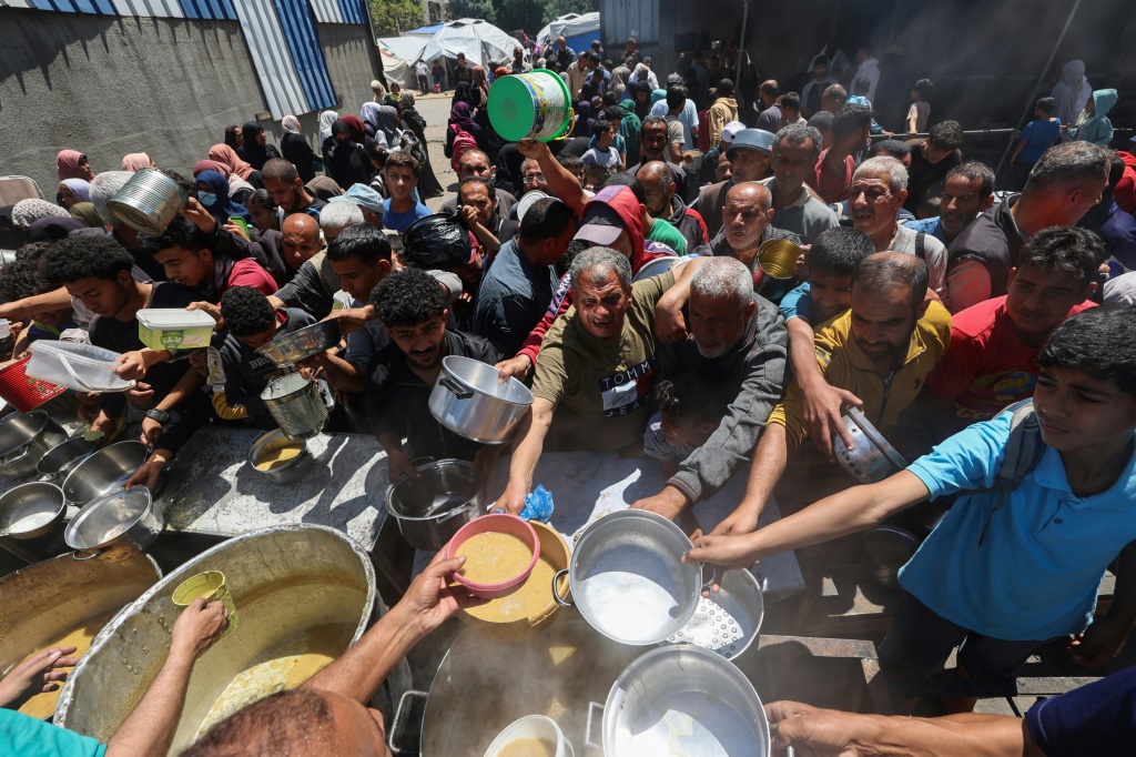 فلسطينيون يقفون في طابور أمام مطبخ يديره برنامج الغذاء العالمي لتوزيع الوجبات على السكان في مخيم النصيرات في قطاع غزة في 26 نيسان/أبريل 2025 (أ ف ب)   