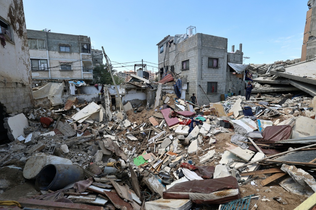     فلسطينيون يتفقدون الأضرار بعد غارات إسرائيلية ليلية على مخيم النصيرات للاجئين في وسط قطاع غزة في 4 أيار/مايو 2025 (أ ف ب)