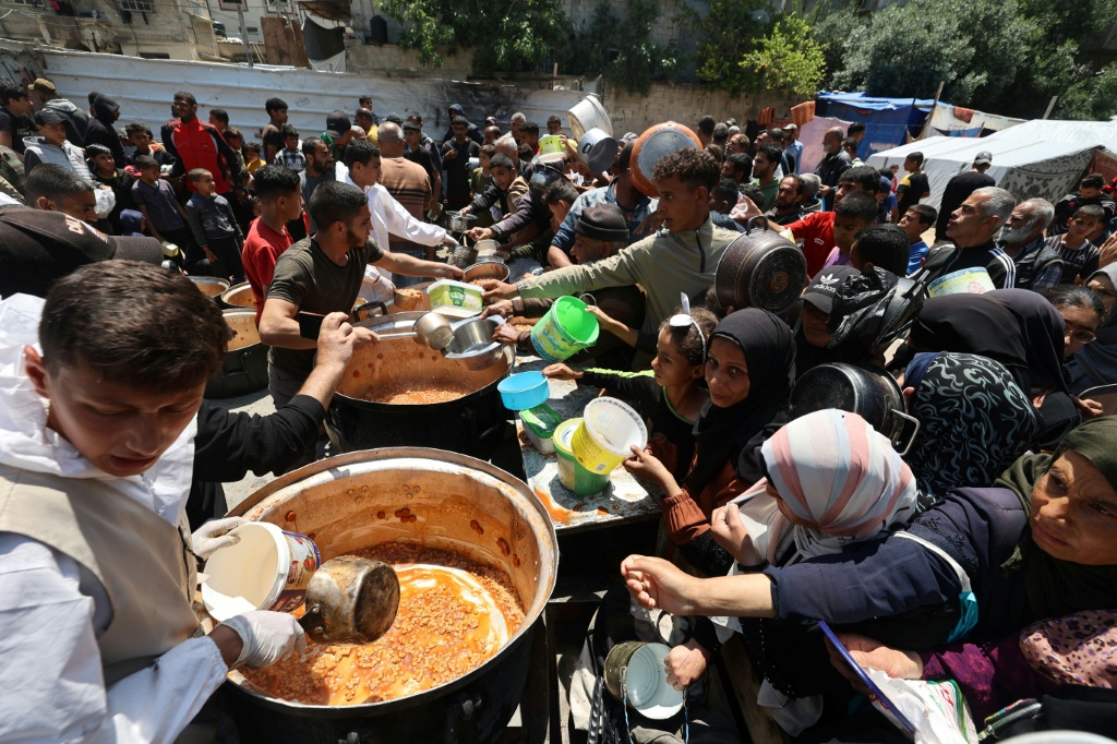  فلسطينيون تجمعو للحصول على الطعام الذي يوزعه مطبخ خيري في مخيم النصيرات للاجئين في وسط قطاع غزة في 5 أيار/مايو 2025 مع تفاقم الأزمة الإنسانية في قطاع غزة المحاصر (أ ف ب)