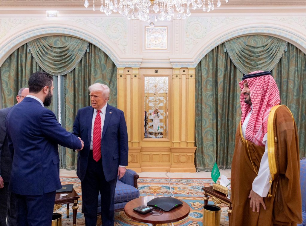 الرئيس الأميركي دونالد ترامب (وسط) يصافح الرئيس السوري الانتقالي أحمد الشرع (يسار) تحت أنظار ولي العهد السعودي الأمير محمد بن سلمان، خلال لقاء في الرياض في 14 أيار/مايو 2025 (أ ف ب)