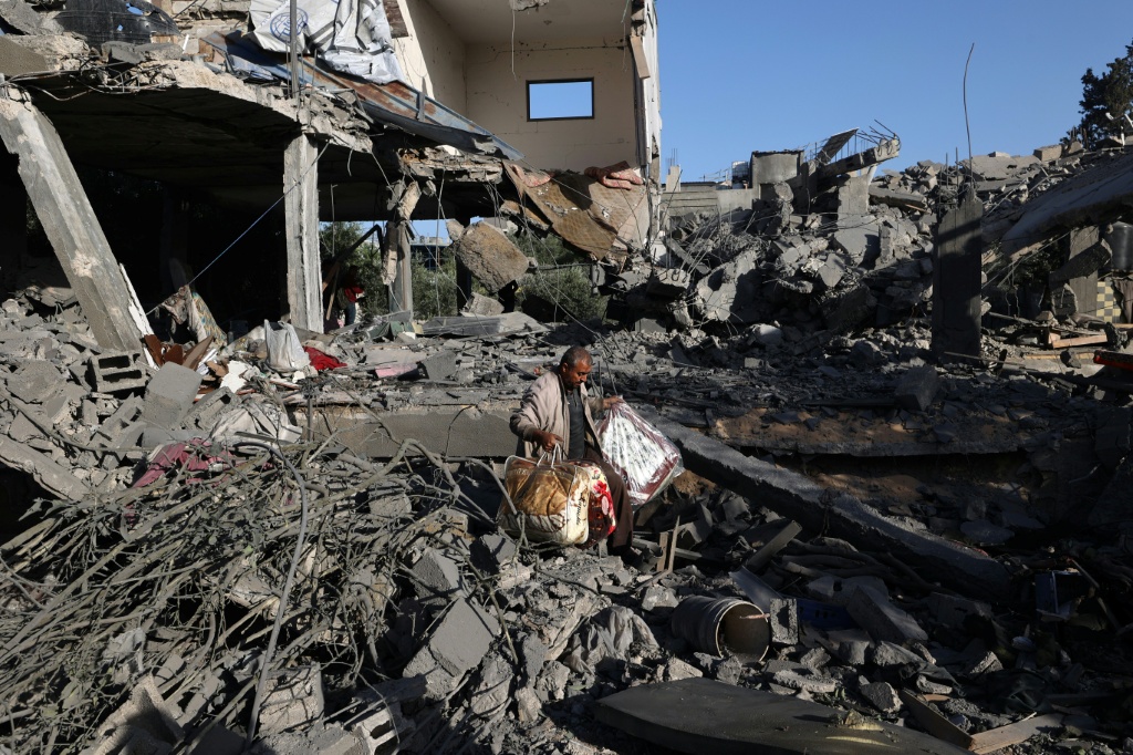 فلسطيني يحمل أغراضا تمكن من إخراجها من منزل استهدفته ضربة إسرائيلية في مخيم النصيرات في قطاع غزة بتاريخ 24 أيار/مايو 2025 (أ ف ب)