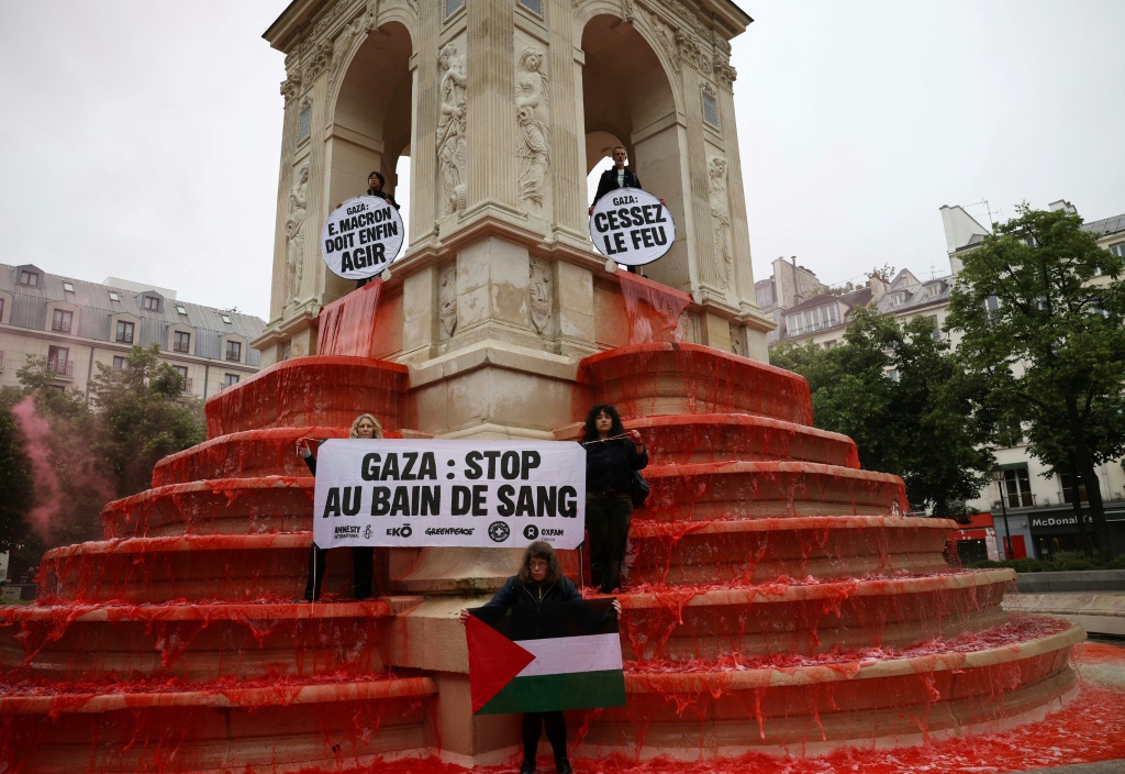 ناشطون مؤيدون للفلسطينيين يحملون العلم الفلسطيني ولافتات بعد صب الطلاء الأحمر في نافورة الأبرياء خلال مظاهرة في باريس، في 28 مايو 2025. (أ ف ب)