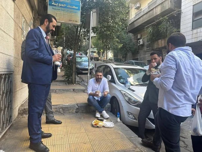 وجبة من الطعام على الرصيف تكسر البروتوكول.. وزير الثقافة السوري يثير ضجة على مواقع التواصل (متداولة على مواقع التواصل الاجتماعي)