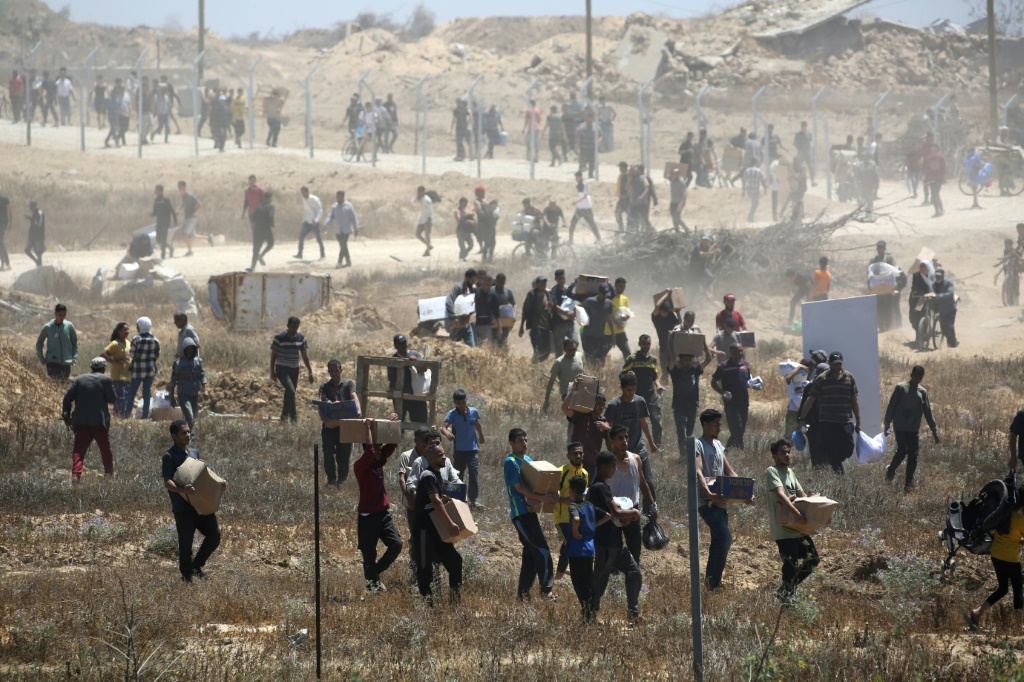 نازحون فلسطينيون يحملون مساعدات إنسانية في مركز توزيع في قطاع غزة في 29 أيار/مايو 2025 (أ ف ب)