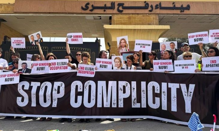 أعضاء امن لبرلمان الإيطالي والأوروبي يحملون لافتات خلال احتجاج أمام الجانب المصري من معبر رفح الحدودي، مطالبين بإنهاء الحرب والسماح بدخول المساعدات إلى قطاع غزة، في 18 مايو/أيار 2025. (أ ف ب)