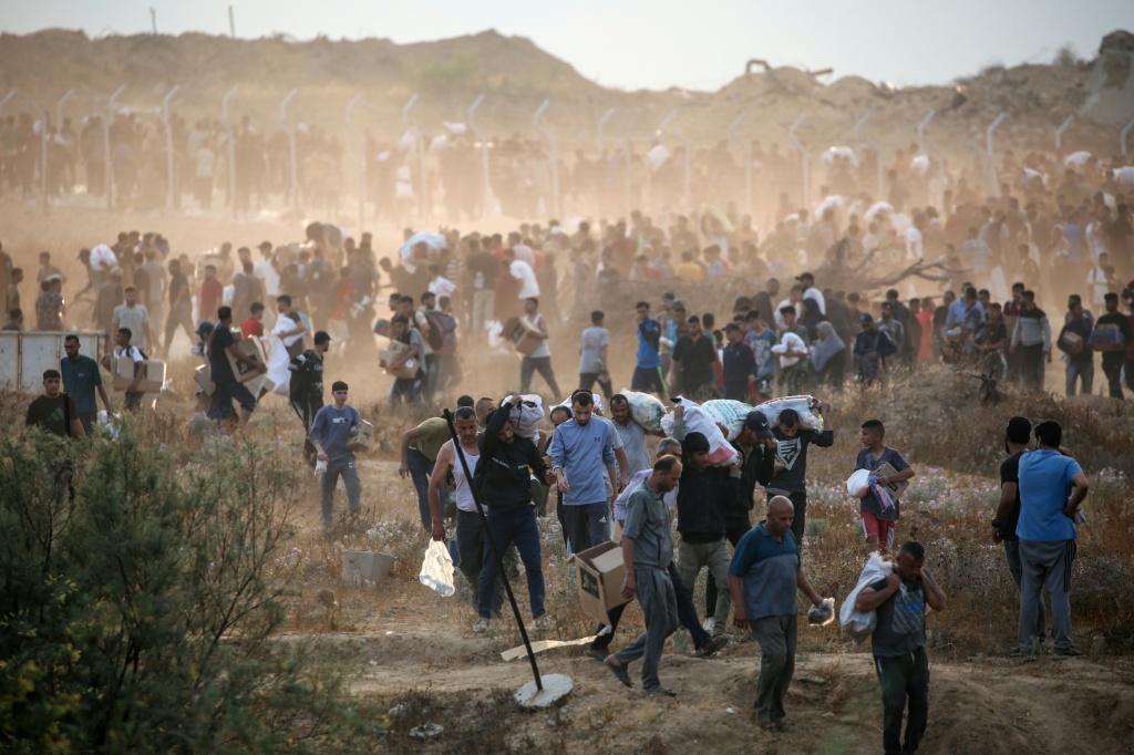 فلسطينيون عائدون بمساعدات غذائية توزعها مؤسسة غزة الانسانية في وسط قطاع غزة في الثامن من حزيران/يونيو 2025 (أ ف ب)