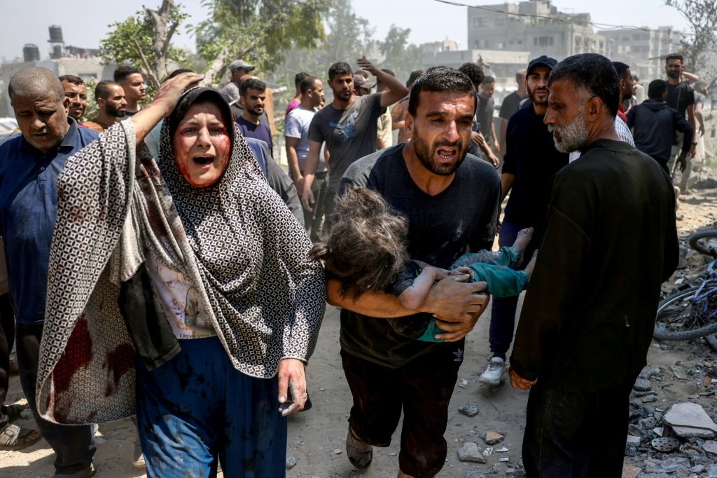 امرأة فلسطينية تصرخ ورجل يحمل طفلاً مصاباً تم انتشاله من بين أنقاض منزل عائلة شاهين الذي استهدفه قصف إسرائيلي في حي الصفطاوي غرب جباليا في شمال قطاع غزة في 9 حزيران/يونيو 2025 (أ ف ب)