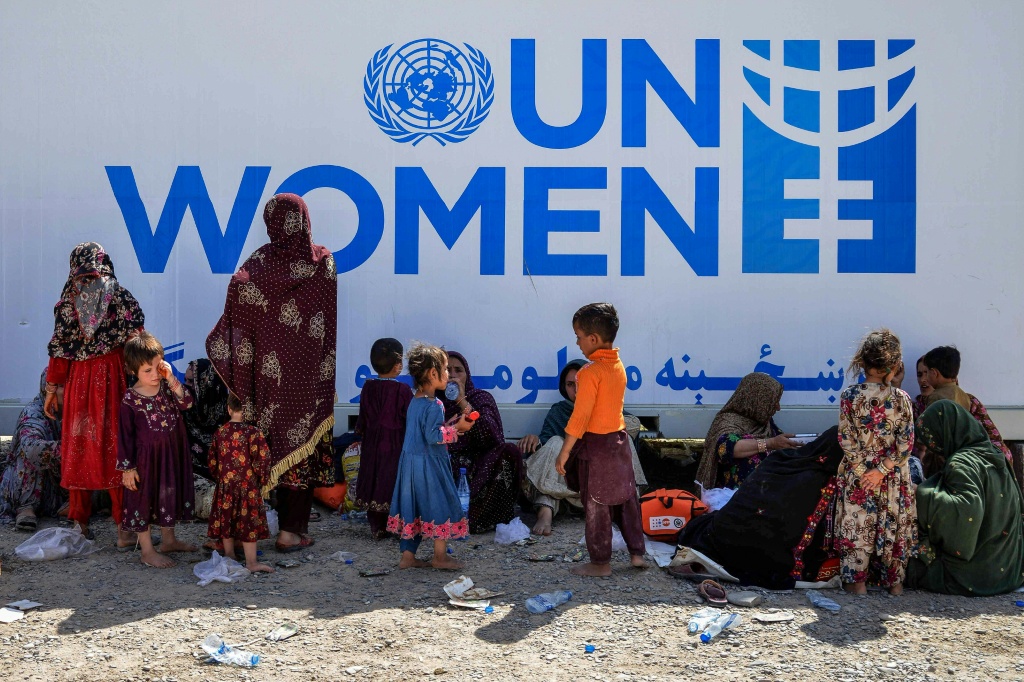 نساء وأطفال لاجئون أفغان يستريحون بالقرب من مكتب معلومات الأمم المتحدة عند وصولهم من باكستان في منطقة تخت بول في ولاية قندهار في 13 نيسان/أبريل 2025 (أ ف ب)