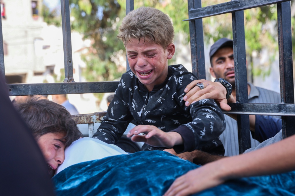 طفل يبكي قرب جثة قتيل في مستشفى الشفاء في مدينة غزة في 18 حزيران/يونيو 2025 (أ ف ب)