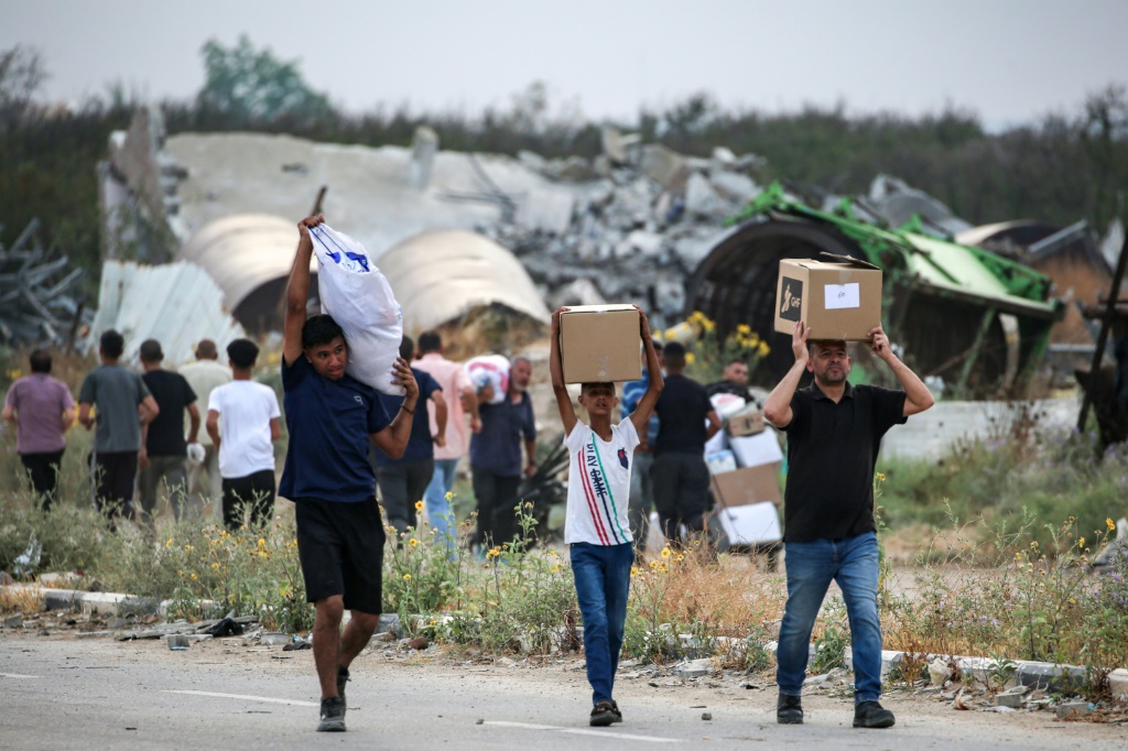 فلسطينيون يحملون مساعدات غذائية من مؤسسة غزة الإنسانية في وسط القطاع في 8 حزيران/يونيو 2025 (أ ف ب)