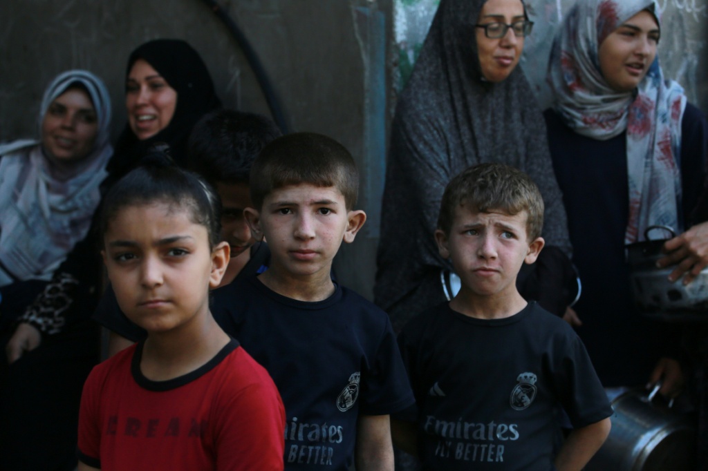 فلسطينيون ينتظرون للحصول على وجبة ساخنة في نقطة توزيع طعام في مدينة غزة في 27 حزيران/يونيو 2025 (أ ف ب)