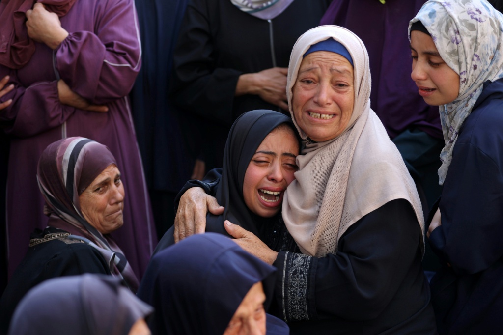 فلسطينيون يبكون أقاربهم الذين قتلوا خلال الغارات الإسرائيلية الليلية، في ستشفى الشفاء في وسط قطاع غزة في 28 حزيران/يونيو 2025 (أ ف ب)