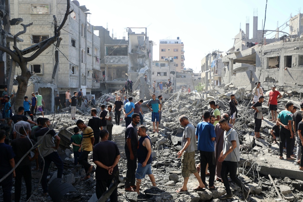 فلسطينيون يتفقدون الأضرار في مخيّم البريج وسط قطاع غزة بعد غارة إسرائيلية في الرابع من تموز/يوليو 2025 (أ ف ب)