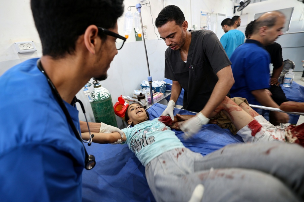 سيدة فلسطينية تحاول تهدئة طفل مصاب وصل إلى مستشفى العودة في النصيرات في قطاع غزة بعد غارة إسرائيلية في 13 تموز/يوليو 2025 حيث أفاد الدفاع المدني بمقتل ما لا يقل عن 31 شخصا في ضربات إسرائيلية متفرقة (أ ف ب)