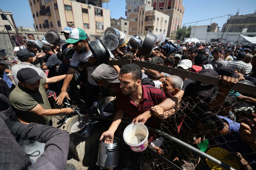 فلسطينيون ينتظرون الحصول على طعام في نقطة توزيع في مخيم النصيرات وسط قطاع غزة في 19 تموز/يوليو 2025 (أ ف ب)