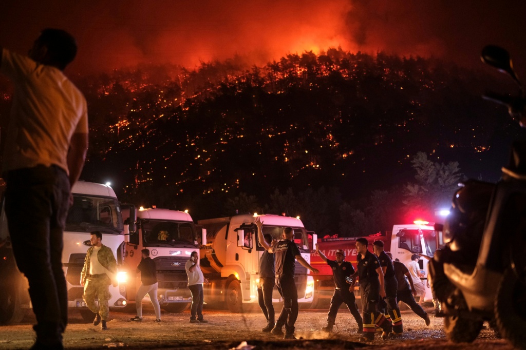 عناصر إطفاء وسكان يحاولون إخماد حريق غابة وسط تصاعد اللهب والدخان في منطقة حرجية في محافظة بورصة بشمال غرب تركيا في 27 تموز/يوليو 2025 (أ ف ب)