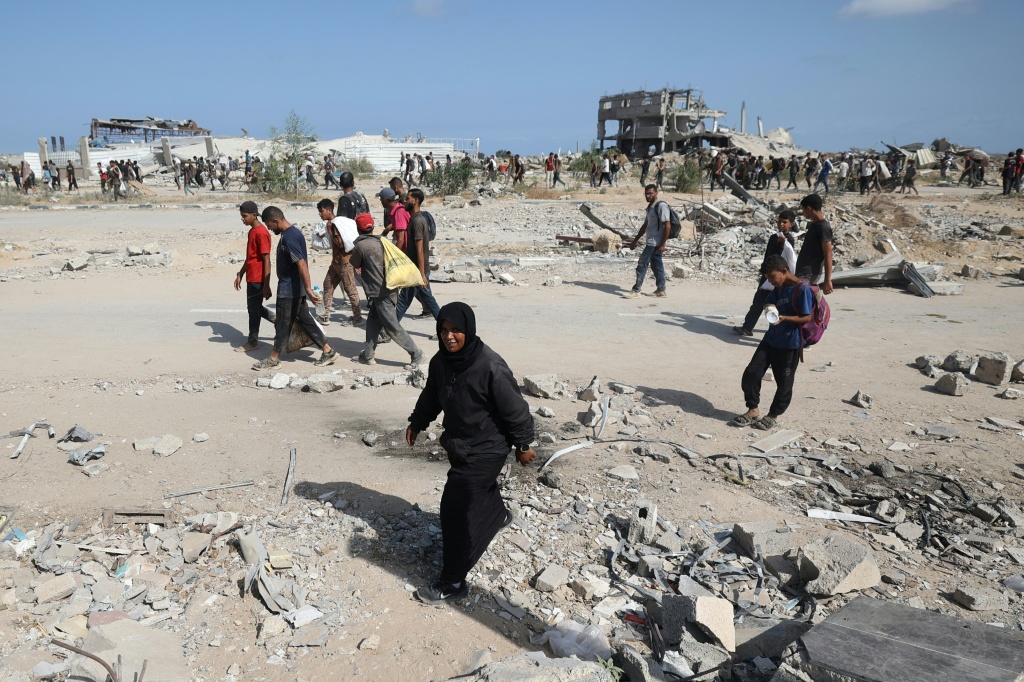 نازحون فلسطينيون في مخيم النصيرات يحملون أكيساسا وطرودا تمكنوا من الحصول عليها من نقطة لتوزيع المساعدات عند ما يسمى "ممر نتساريم" في وسط قطاع غزة في 30 تموز/يوليو 2025 (أ ف ب)