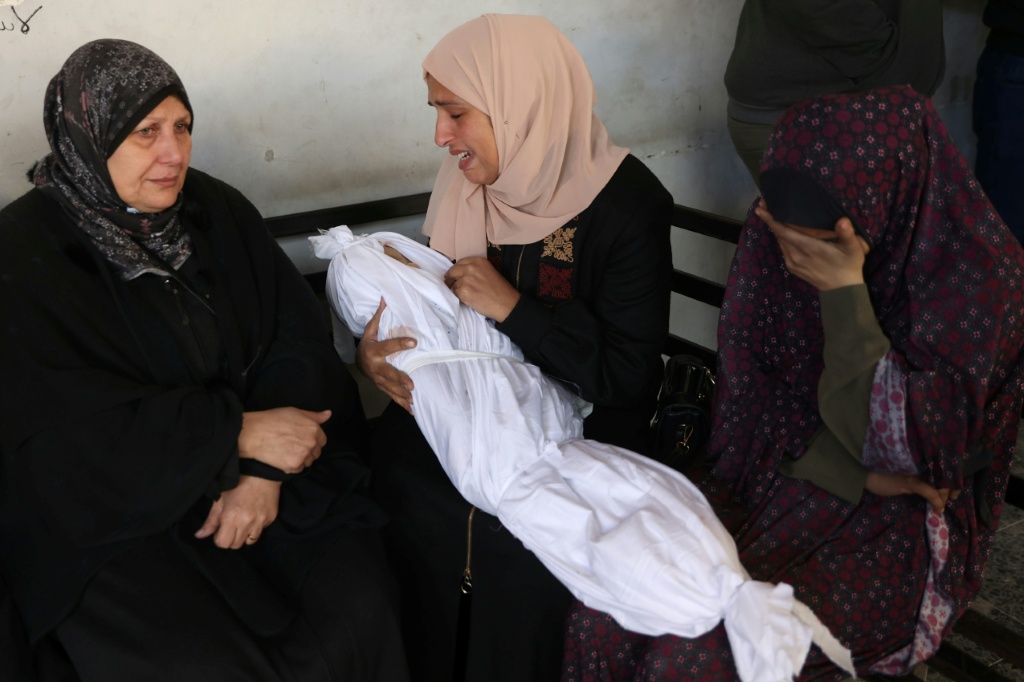 نازحون فلسطينيون في مخيم النصيرات يحملون أكيساسا وطرودا تمكنوا من الحصول عليها من نقطة لتوزيع المساعدات عند ما يسمى "ممر نتساريم" في وسط قطاع غزة في 30 تموز/يوليو 2025 (أ ف ب)