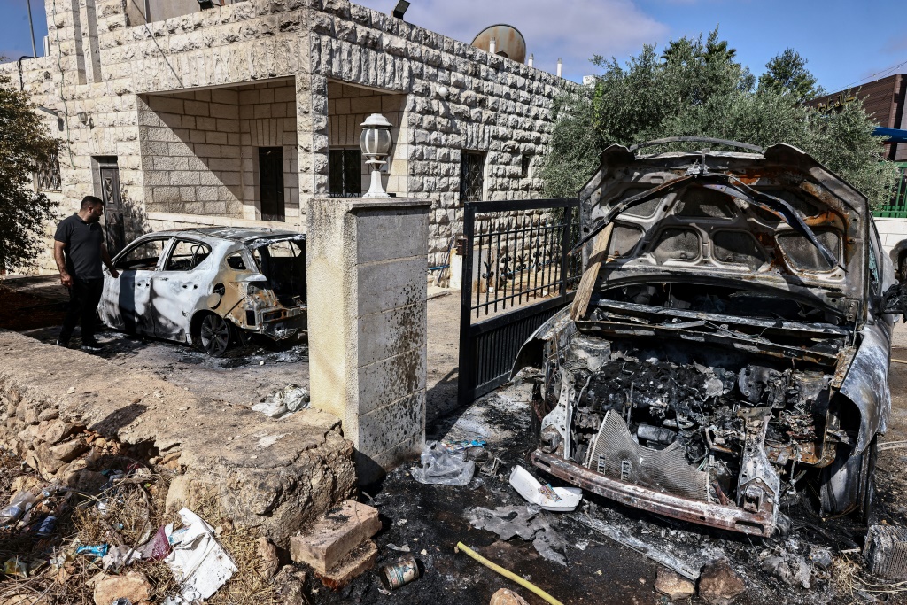فلسطينيون يتفقدون الأضرار الناجمة عن هجوم لمستوطنين إسرائيليين على قرية سلواد وسط الضفة الغربية المحتلة في 31 تموز/يوليو 2025 والذي أدى إلى مقتل فلسطيني اختناقا (أ ف ب)