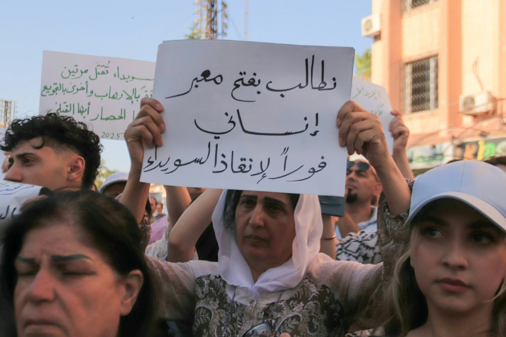  سورية ترفع لافتة خلال احتجاج على الوضع الإنساني في مدينة السويداء ذات الأغلبية الدرزية في 28 تموز/يوليو 2025 (أ ف ب)