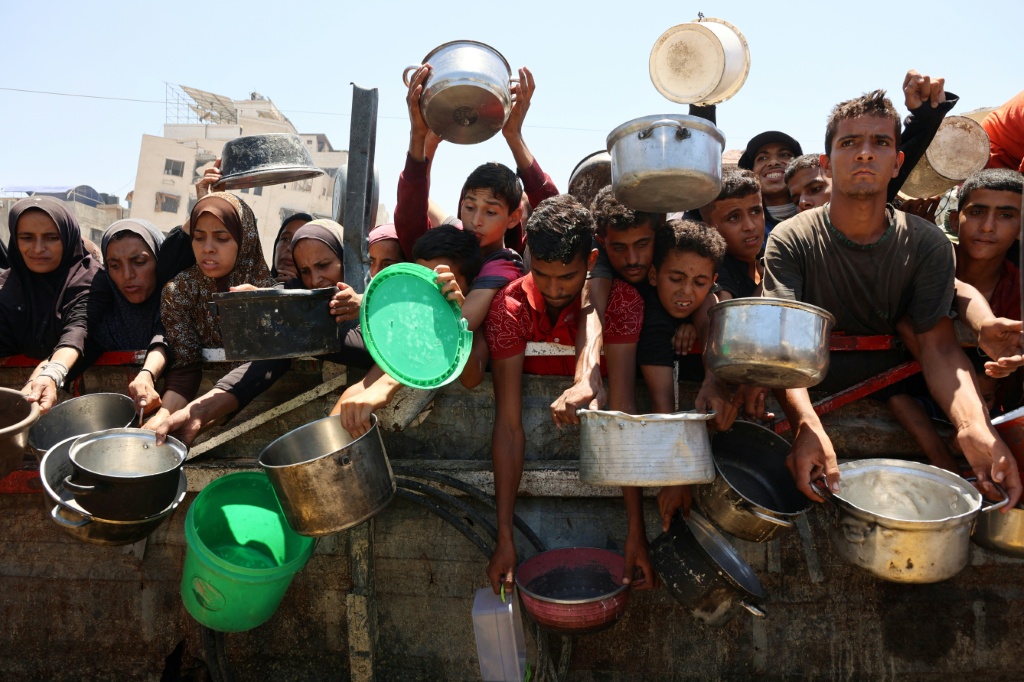 فلسطينيون يتلقون حساء عدس في نقطة توزيع أغذية في مدينة غزة في 2 آب/أغسطس 2025 (أ ف ب)