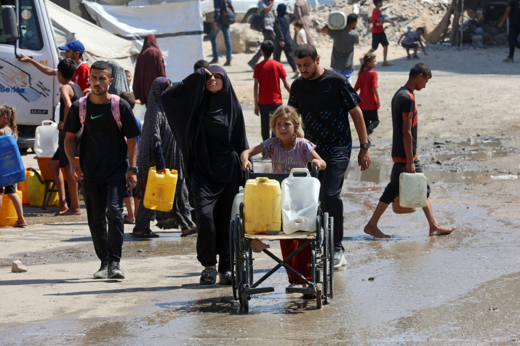 فلسطينيون يتسلمون المياه من نقطة توزيع في مدينة غزة في الأول من آب/أغسطس 2025 (أ ف ب)