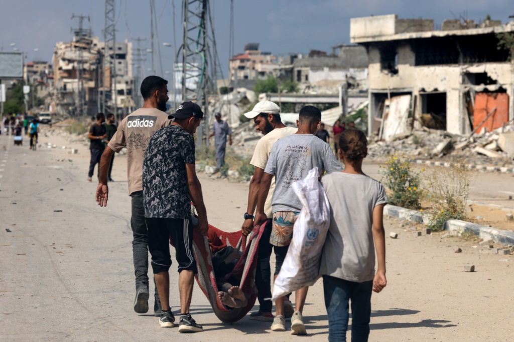 طفلة فلسطينية تسير خلف شبان يحملون جثمان شخص قتل خلال بحثه عن طعام قرب مركز توزيع المساعدات التابع لمؤسسة غزة الإنسانية الاميركية في شارع صلاح الدين وسط قطاع غزة في الرابع من آب/أغسطس 2025 (أ ف ب)