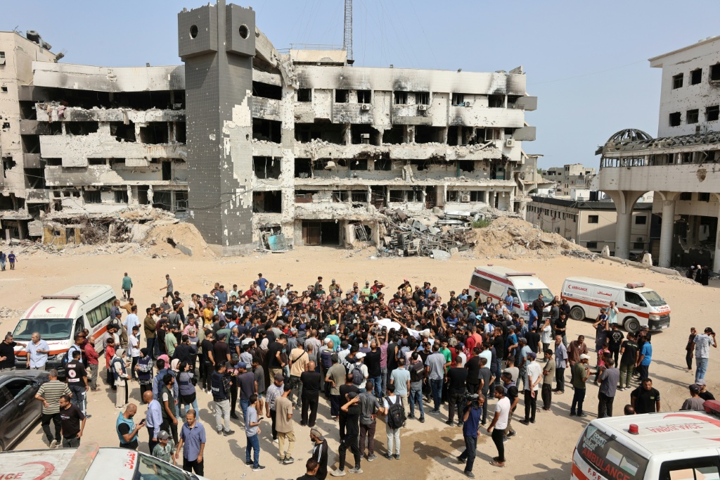 مشيعون يحملون جثامين فلسطينيين، بينهم صحافيون ومسعف، قُتلوا في غارة إسرائيلية، قبل جنازة جماعية خارج مستشفى الشفاء في مدينة غزة في 11 آب/أغسطس 2025 (أ ف ب)