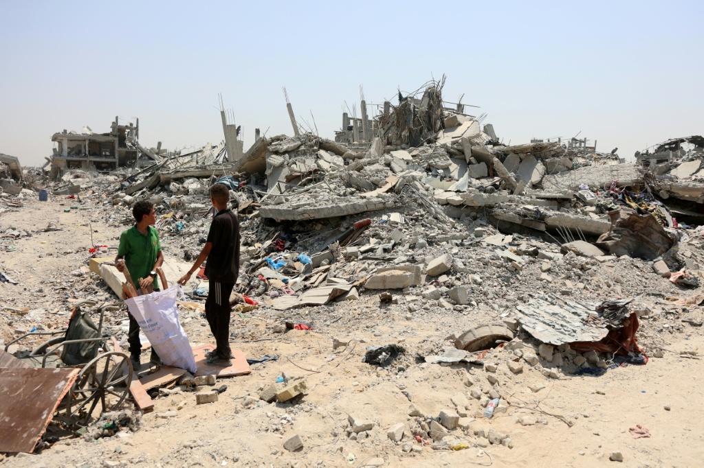 فتيان فلسطينيان وسط ركام في حي التفاح في مدينة غزة في 14 آب/أغسطس 2025 (أ ف ب)