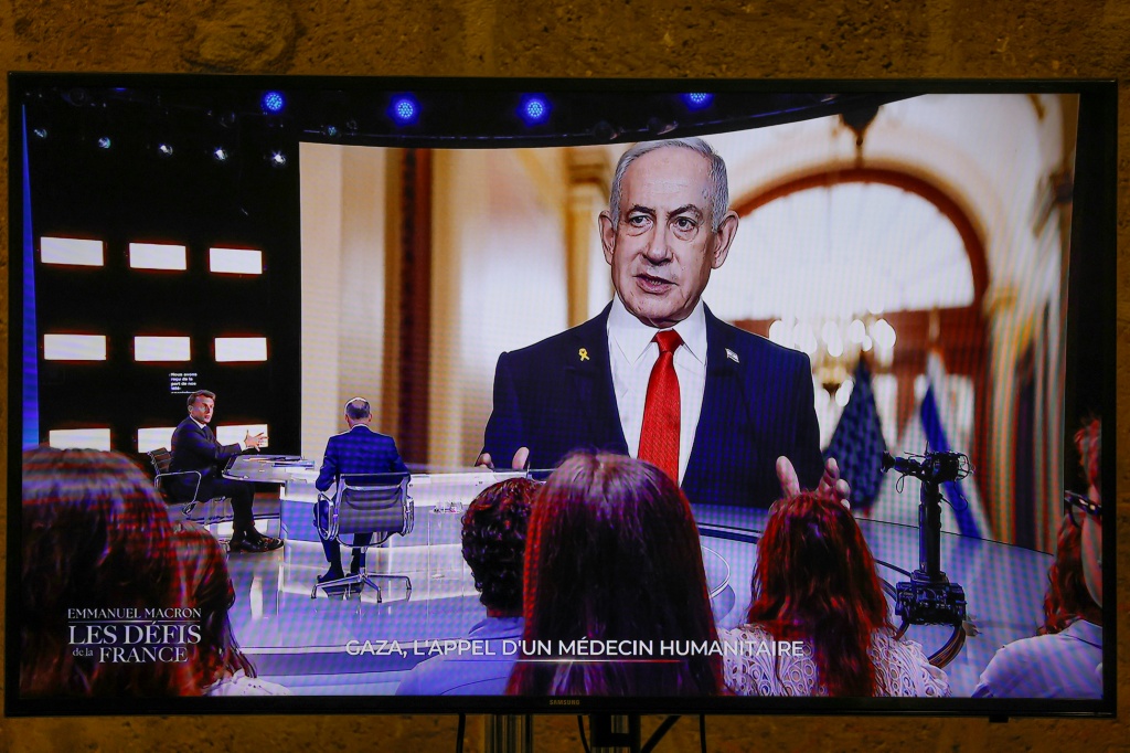صورة مؤرخة في 13 أيار/مايو 2025 تظهر الرئيس الفرنسي إيمانويل ماكرون مع محاور من قناة "تي إف 1" وصورة رئيس الوزراء الاسرائيلي بنيامين نتانياهو خلفه (أ ف ب)