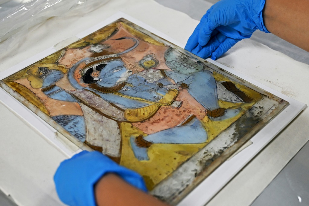 موظف يعمل على لوحة زجاجية للإله الهندوسي هانومان في قسم الحفاظ على التراث في مركز أنديرا غاندي الوطني للفنون في نيودلهي عاصمة الهند في 20 حزيران/يونيو 2025 (أ ف ب)